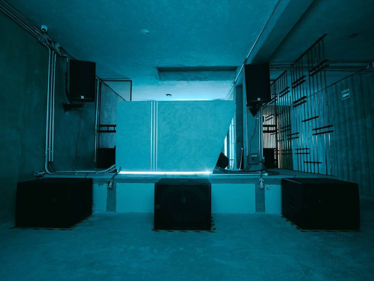 Cabina de DUNA CLUB frente a la pista, con subgraves a nivel de piso y luz cyan.